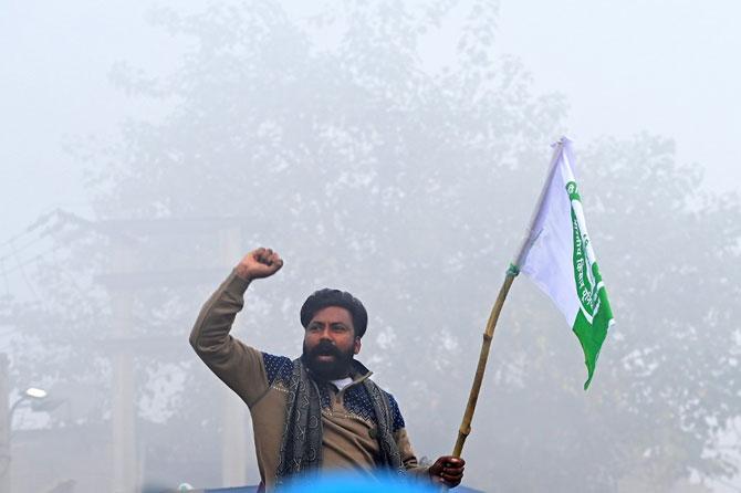A farmer shouts slogans next to a police barricade amid foggy condition during a nationwide general strike to protest against the new farm laws at the Delhi-Haryana state border in Singhu on December 8, 2020.