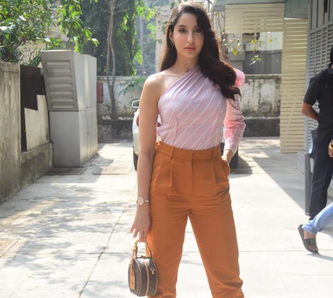 Nora Fatehi was clicked at an entertainment management office in Bandra, Mumbai. The Dilbar actress sizzled in her off-shoulder crop top and orange pants. A pair of grey handbag along with a bit of make-up completed her look. (All pictures: Yogen Shah).