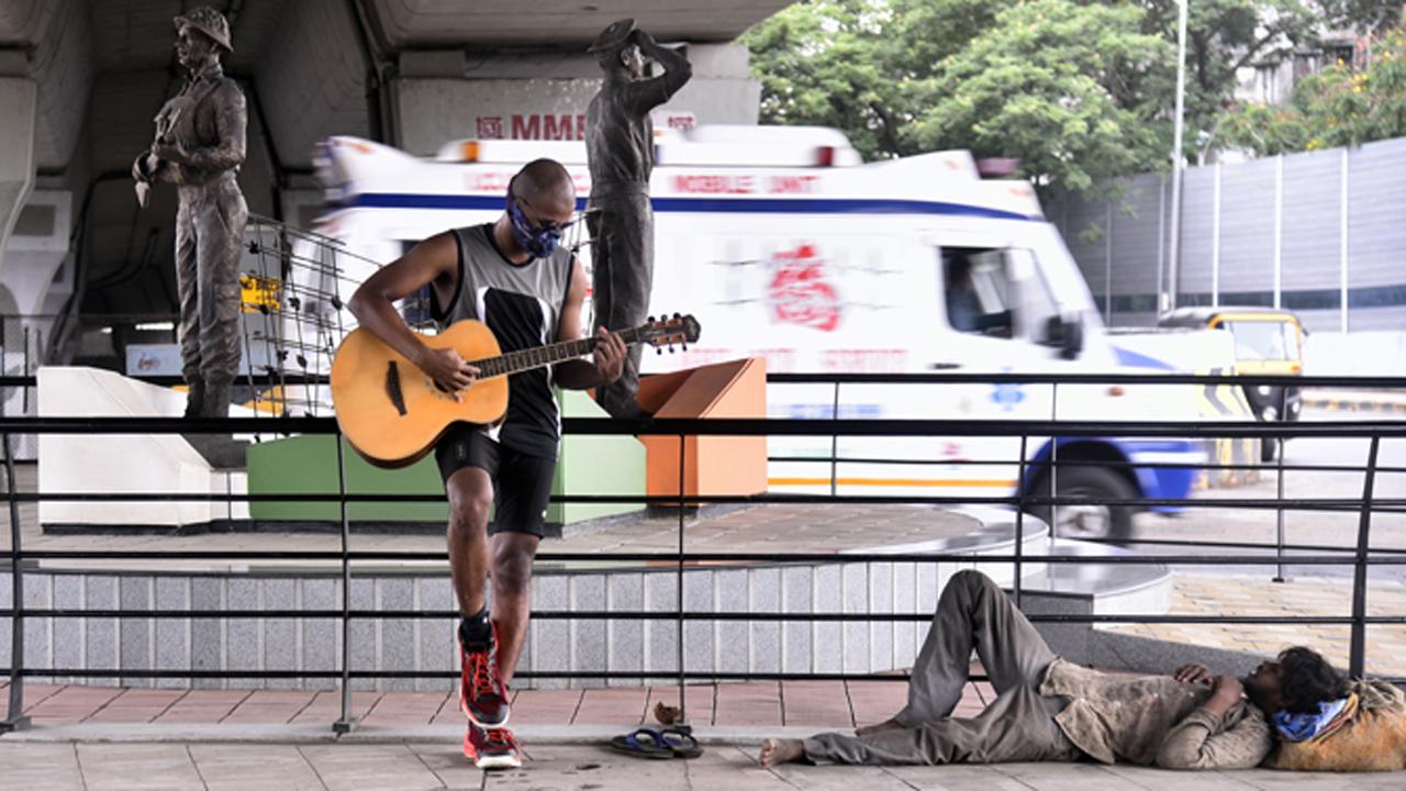 A guitarist plays a song on the streets of Chembur as a homeless man takes a nap while an ambulance whizzes behind him.
Photo: Pradeep Dhivar