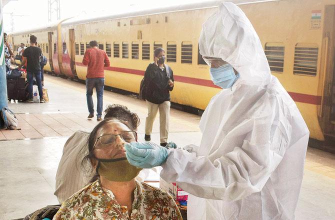 A civic health worker takes a swab sample from a passenger at Dadar railway station. File pic /Ashish Raje