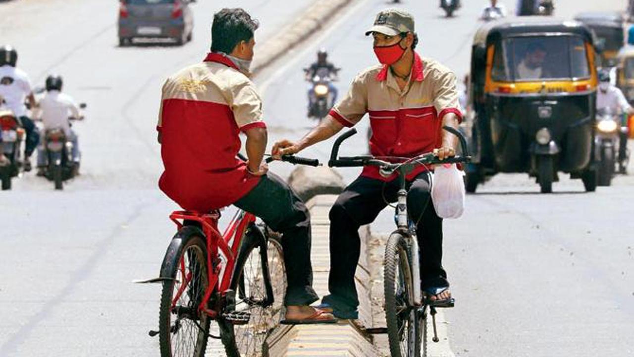 Two delivery boys chit-chat on the Western Express Highway in Goregaon East while delivering food parcels during the COVID-19 enforced lockdown in Mumbai.
Photo: Anurag Ahire