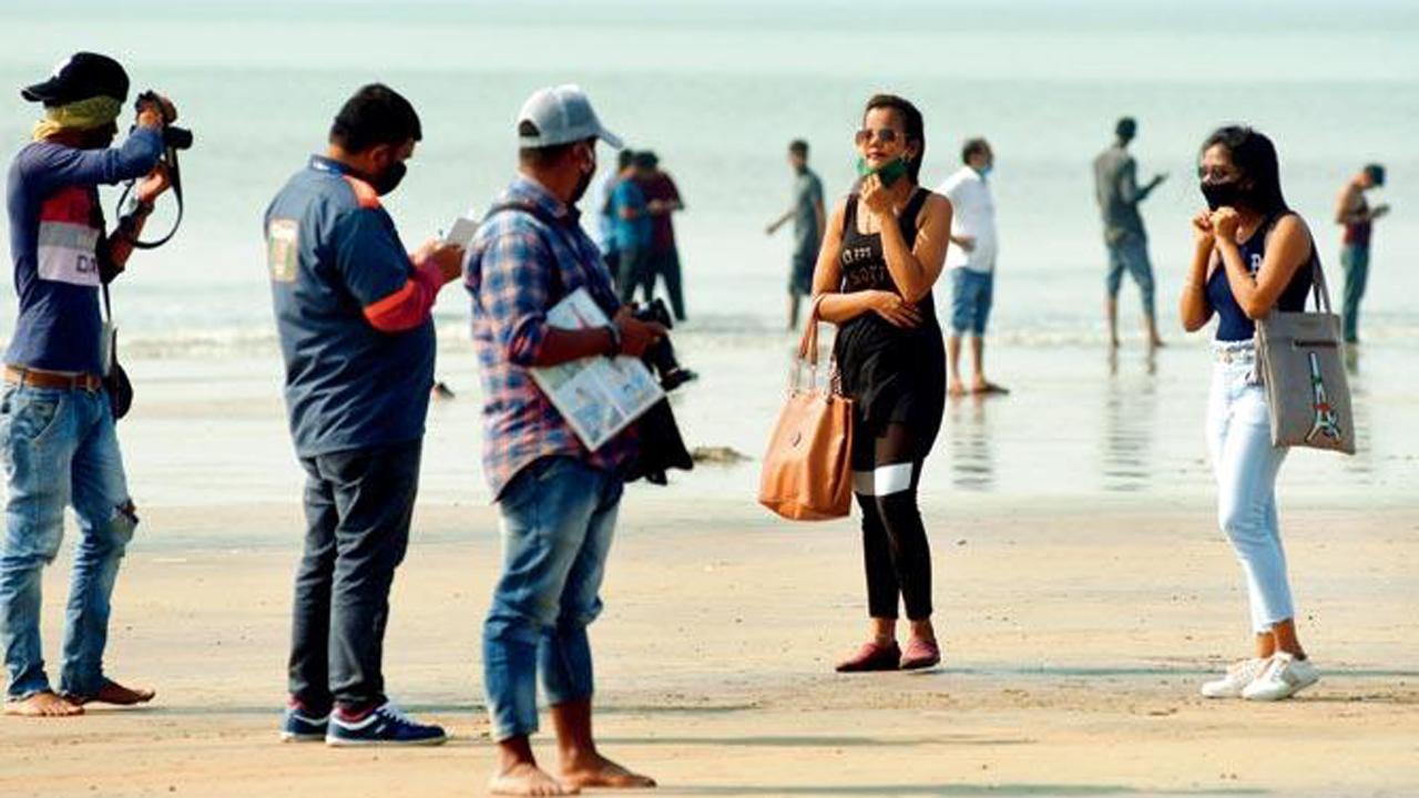 A BMC staffer fines youngsters roaming without masks at Juhu beach as Mumbai opens up after being under lockdown.
Photo: Atul Kamble