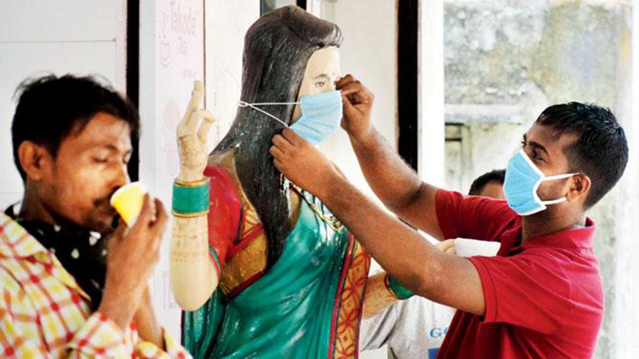 A shop owner in Matunga Labour Camp places a mask on a mannequin as a passerby sips his morning tea.
Photo: Ashish Raje