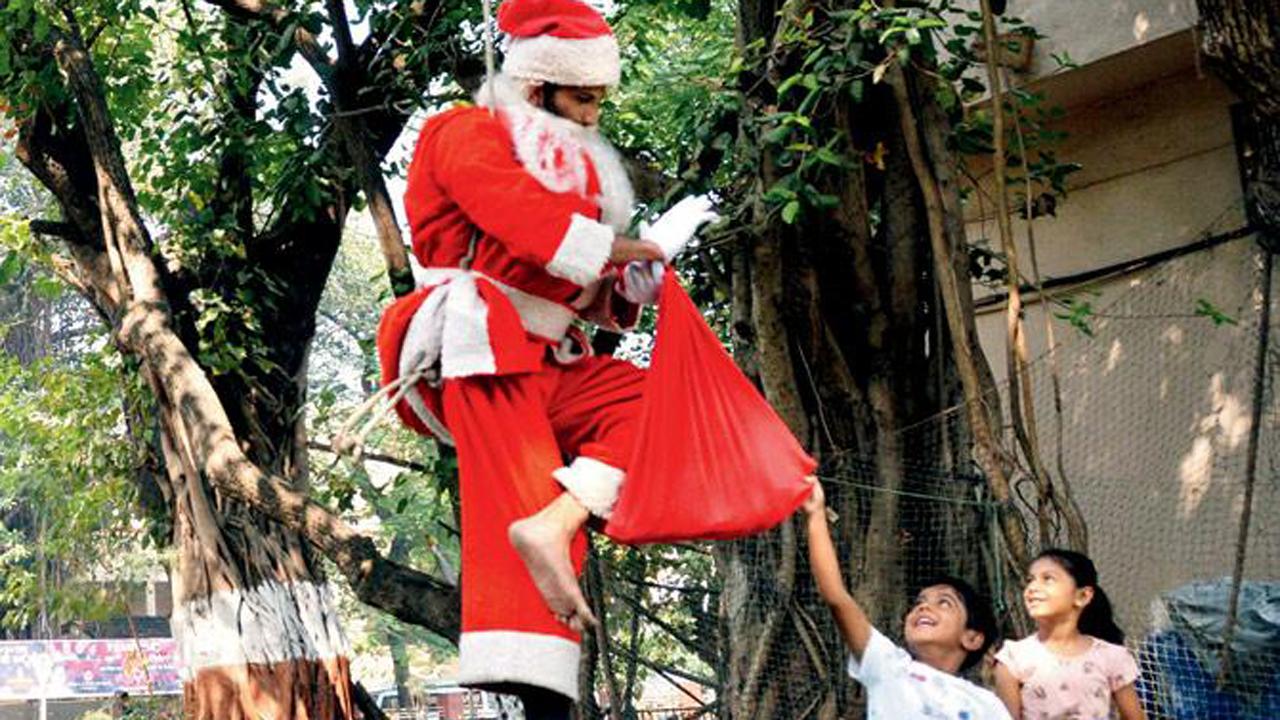 A man dressed as Santa Claus climbs on a tree and teases children who try to reach him for gifts, at Shivaji Park in Dadar West.
Photo: Sayyed Sameer Abedi
