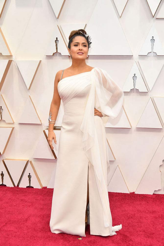 Salma Hayek's outfit was a true winner at the red carpet event of 92nd Academy Awards. She was seen wearing an asymmetrical thigh-high slit gown, which she paired with silver accessories.