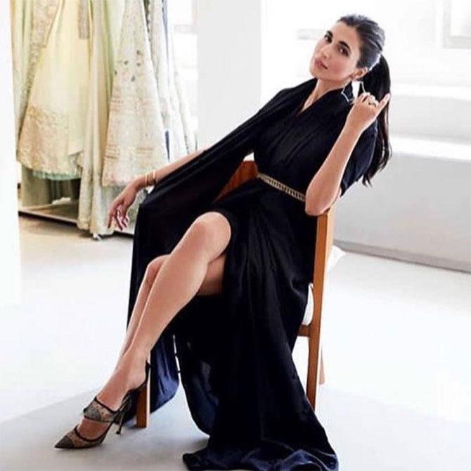 She strikes a gracious pose in this flowy black belted dress, with her hair tied into a ponytail.