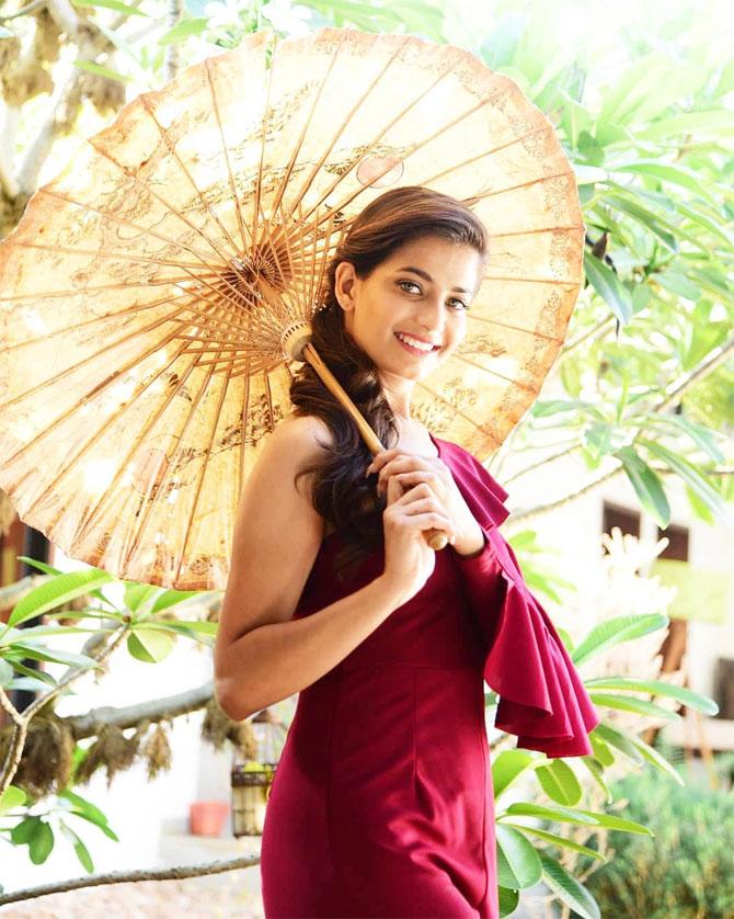 In another off-shoulder dress with frills, she poses charmingly holding a bamboo umbrella. 