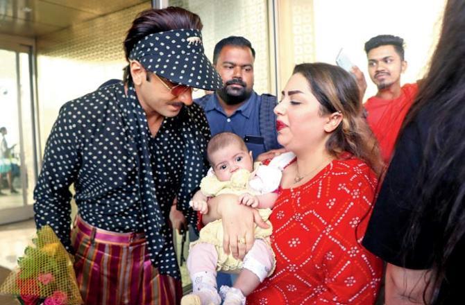 Is actor Ranveer Singh, once again dressed in his inimitable style, sharing some words of wisdom with the toddler he met at the airport? Pic/Anurag Ahire