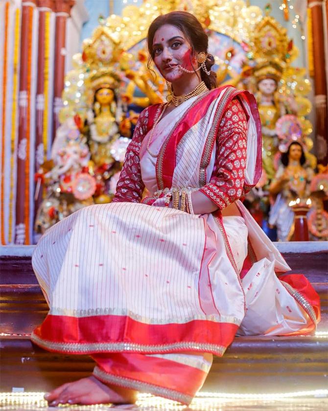 In this stunning picture, Nusrat Jahan looks poised and poignant as she stuns in a Bengali saree in hues of red and white. The TMC MP can be seen sporting a red blouse which she paired with a red bindi on her forehead.