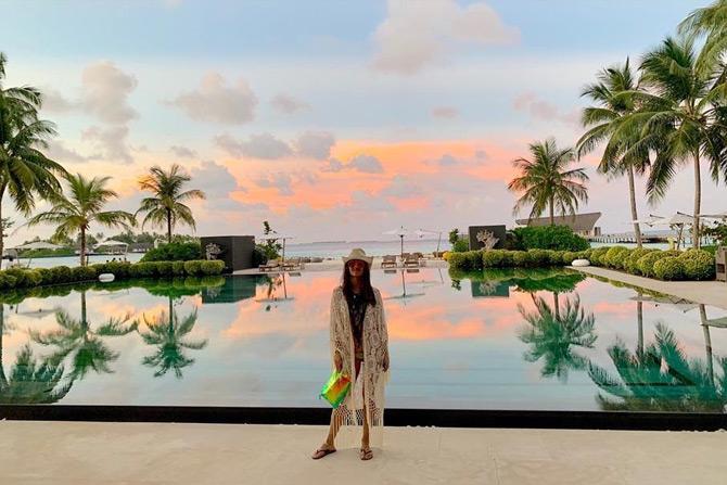 In photo: Natasha Poonawalla poses amidst the backdrop of a stunning pool overlooking an exotic beach
