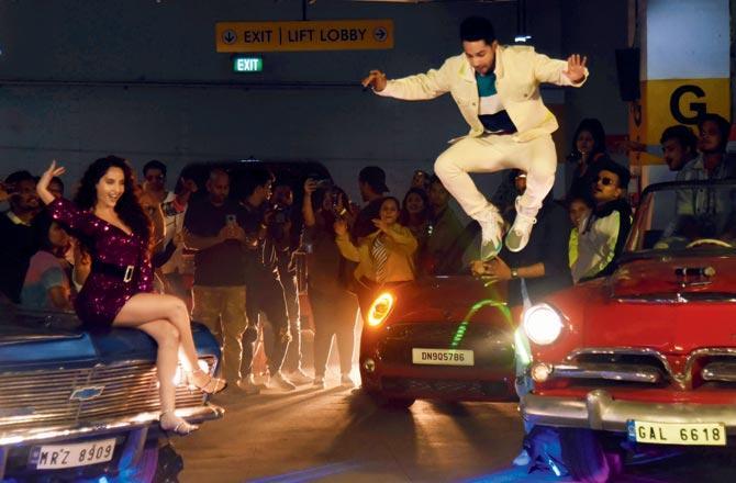 It looks like Varun Dhawan is a true acrobat until you notice a person aiding him in the background at the launch of a song he features in with Nora Fatehi. Pic/Sameer Markande