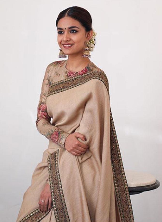 South Indian actress Keerthy Suresh looked enchanting at the 66th National Film Awards in New Delhi in a light brown saree with a flower-printed blouse and traditional big jhumkas by Sabyasachi. Her plain saree spoke volumes because of the earrings and the light makeup.