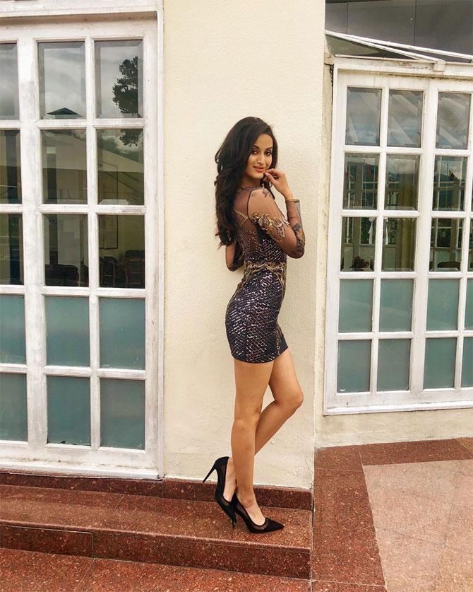 She carries herself with poise in this sheer black thigh-high dress and stillettos.