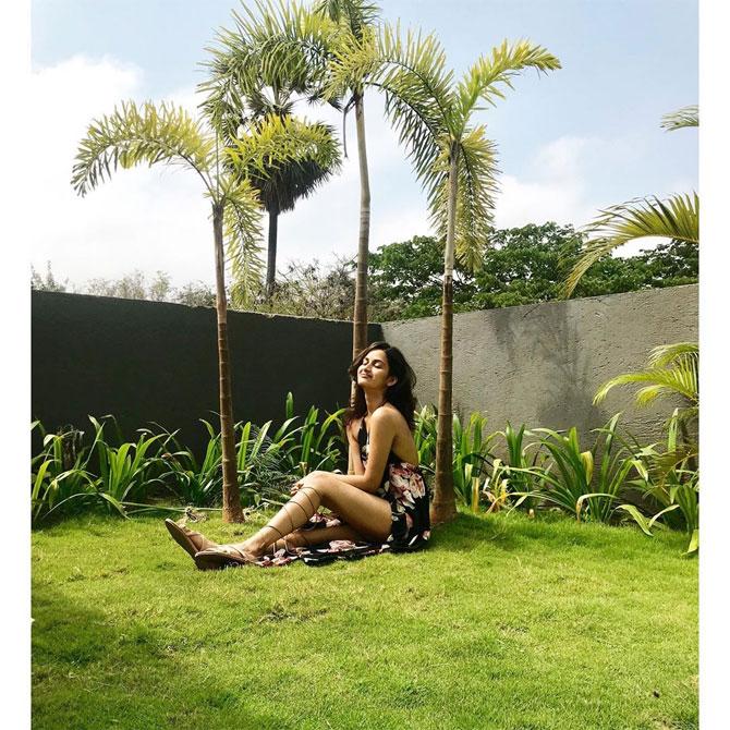 She shows off her well-toned legs while giving summer vibes in this black, floral printed halter gown.