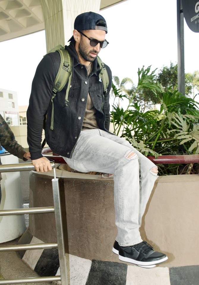 Disha's Malang co-star Aditya Roy Kapur seen jumping over the fence as he arrives at the Mumbai airport. Aditya sported a casual look a tee, denim jacket and distressed denim with a cap.