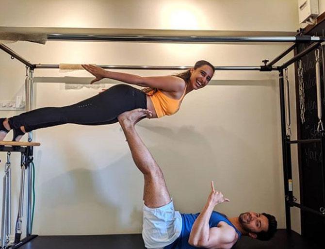 Namrata Purohit balances herself on Varun Dhawan's feet as he puts them up in the air.