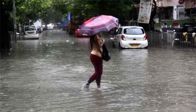 In picture: A woman wades through an inundated road in Sion.