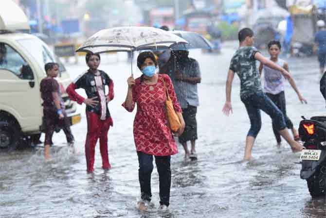 According to BMC's Disaster Control department, most parts of south Mumbai received between 4 to 6cm of rain, resulting in waterlogging at some spots and hindering traffic flow.
In picture: A woman walks through a waterlogged street as children enjoy the heavy downpour