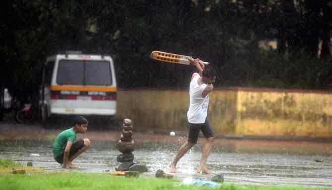 A group of youngsters enjoy a game of cricket at a ground.