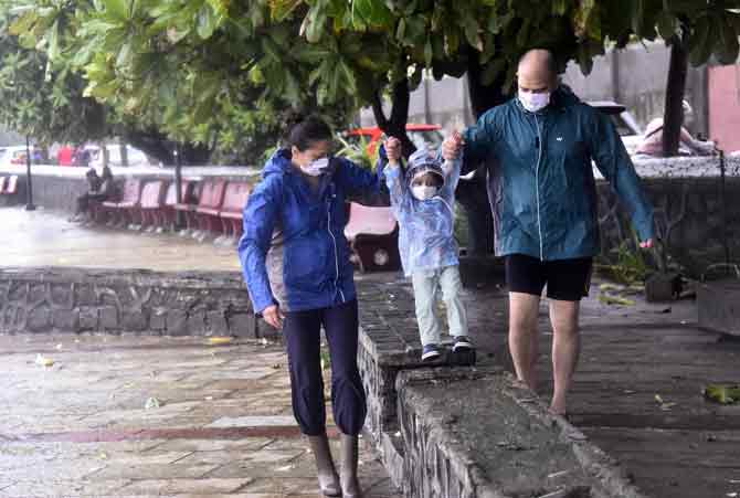 A child enjoys the rain with his parents near the seashore at Bandra bandstand.