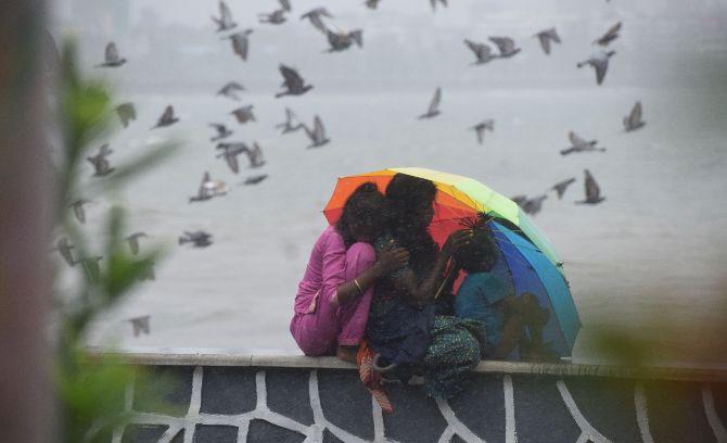 In photo: A woman uses an umbrella to cover herself from rains at Girgaon Chowpatty.