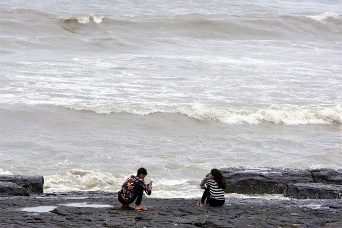 In photo: A boy taking a photograph of a friend by the seashore in Bandra.