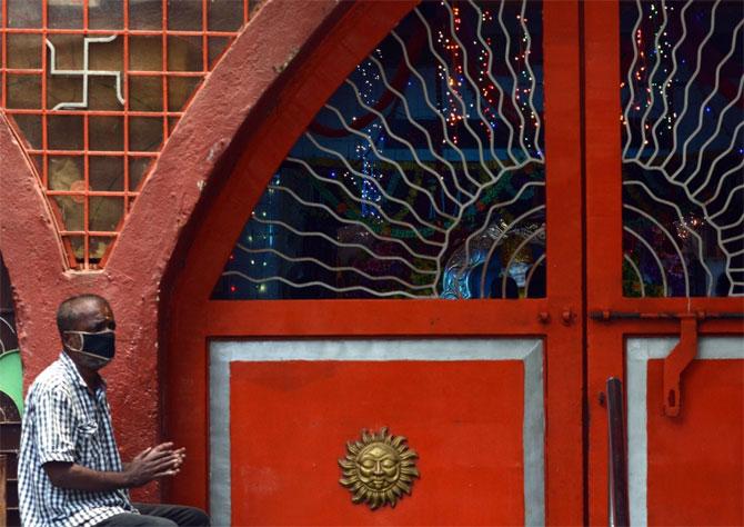 A devotee offers prayers outside a temple as Kurar village went under complete lockdown to curb the spread of COVID-19.