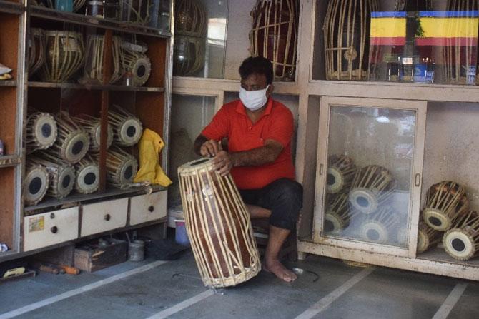 A shopkeeper repairs a Dholak - a two-headed hand-drum, at his shop in Lalbaug, Parel.