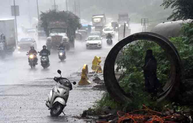 To avoid getting wet, a man takes shelter in a pipe lying on the roadside in Mira Road.