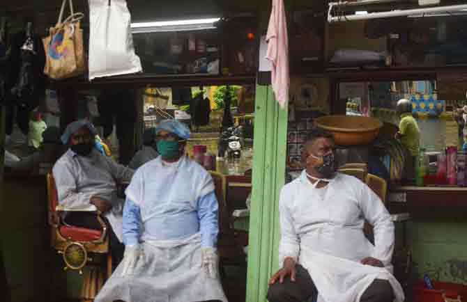 Roadside barbers patiently wait for customers while taking the necessary precautions as per the COVID-19 protocol amid heavy rains. 