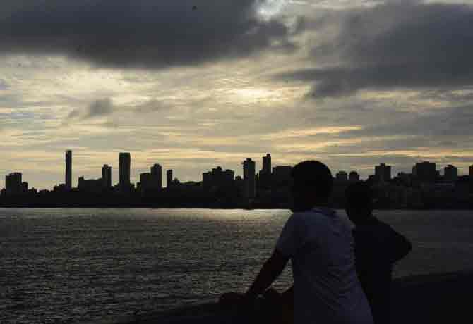 People watch the sunset and enjoy the view of the city's skyline amid dark clouds hovering over them in Malabar Hill.