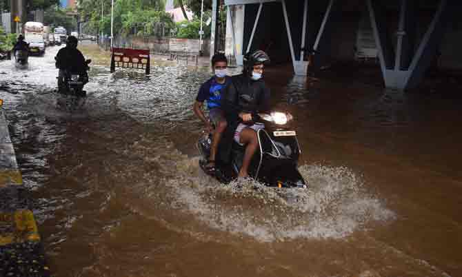 Two motorists enjoy a ride through a waterlogged road.