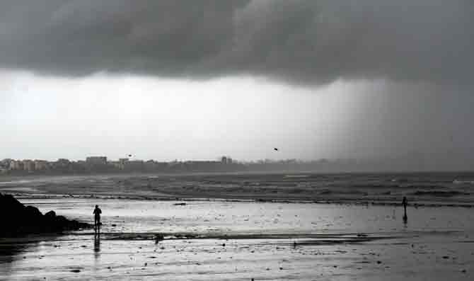People are seen taking a stroll and enjoy the pleasant weather at Versova beach. 