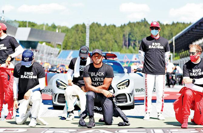 Hamilton (left) and Sebastian Vettel take a knee before the Austrian Grand Prix race at Spielberg yesterday. While all drivers wore a black T-shirt with End Racism inscribed on it, six did not perform the gesture