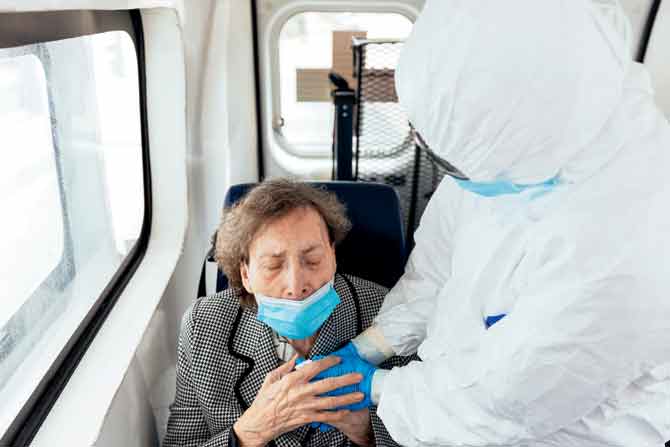 In this file photo taken in April, an elderly woman with COVID-19 holds the hands of a Spanish Red Cross volunteer as she is transferred from the Pyrenees residence to another residence where only Coronavirus infected are housed