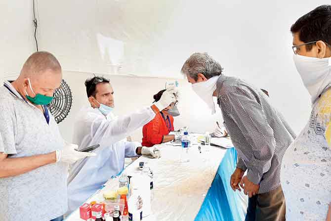 BMC health workers examine residents of IC Colony at a fever camp at Samaj Kalyan Ground, Borivli. FILE PIC
