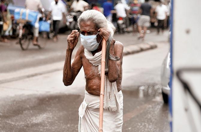 A senior citizen adjusts his mask, at Dharavi on Monday. Pic/Pradeep Dhivar