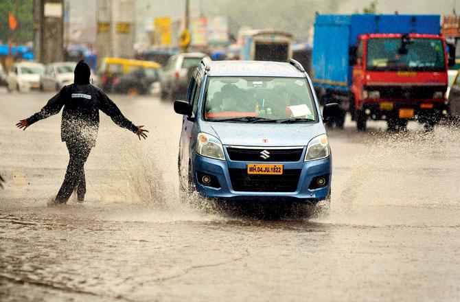 People drive through a flooded street in Wadala on Tuesday. Pic/Shadab Khan