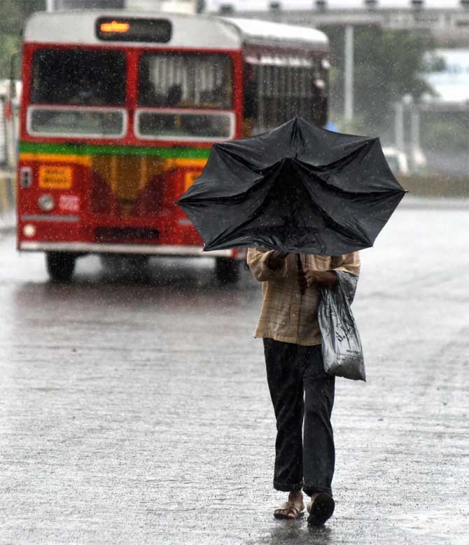 In picture: A man struggles to straighten his umbrella amid strong winds and heavy rain.