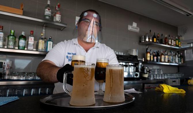 A waiter wearing a face shield prepares some beers to be served at the bar's terrace in La Malvarrosa beach in Valencia as some Spanish provinces are allowed to ease lockdown restrictions amid the coronavirus outbreak.