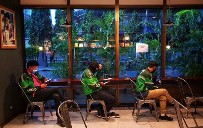 Food delivery riders observe social distancing as a preventive measure against the spread of the COVID-19 novel coronavirus while waiting to pick up orders at a restaurant in Bangkok.