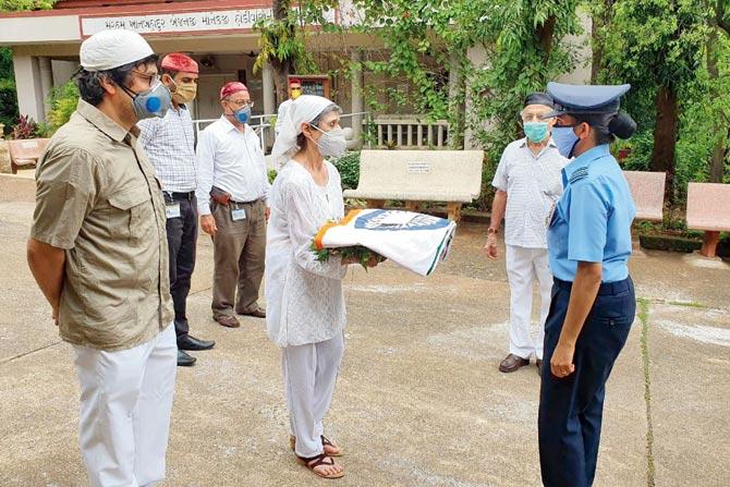 An Air Force officer hands over a tricolour to his wife as Squadron Leader (retd) Parvez Rustom Jamasji is cremated with full military honours, at Doongerwadi on Friday