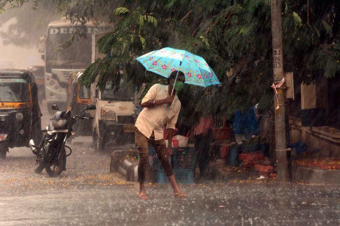 In photo: A man armed with a face mask and an umbrella tries to protect his clothes from getting wet as heavy rains lash the city.