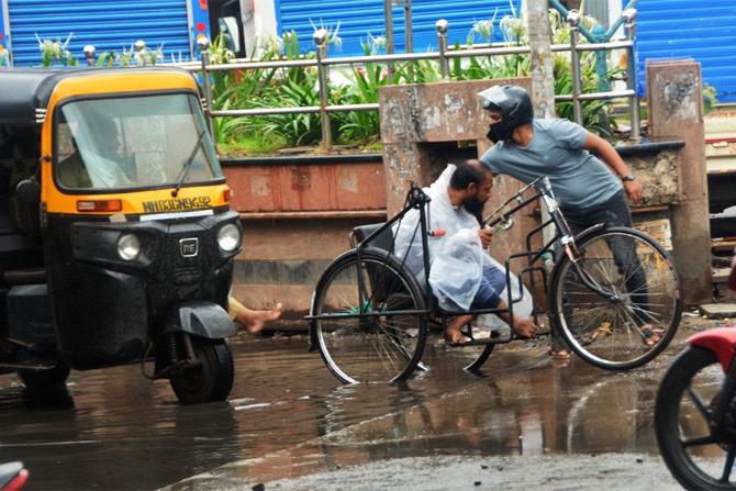 In photo: A man and a auto-rickshaw driver help a differently abled person in Kurla.