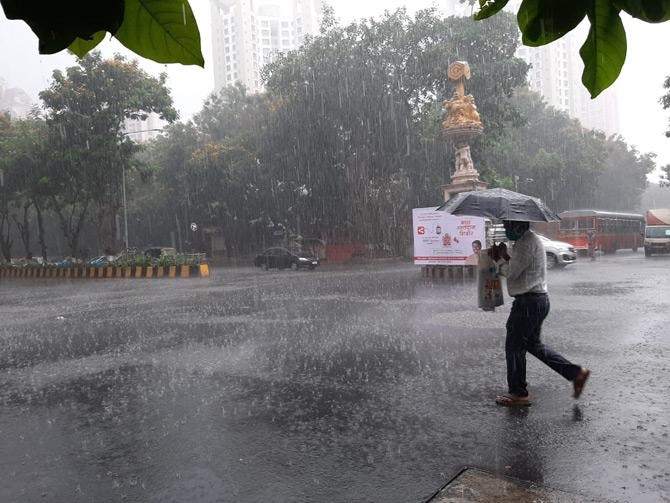 In photo: A man armed with face mask and umbrella rushes to reach work as city receives heavy rainfall.