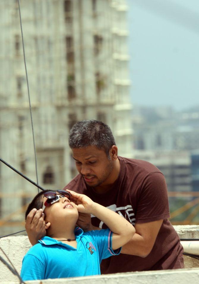 In photo: A father helps his son observe the annual solar eclipse at Hiranandani in Powai.