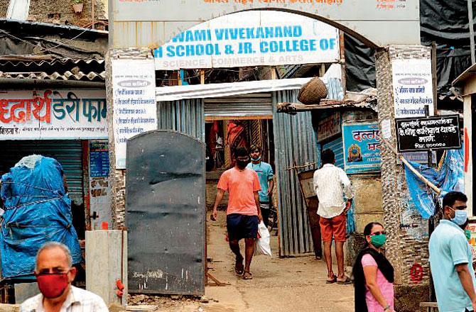 Residents pass through narrow passages at entry and exit points in Appapada, Malad