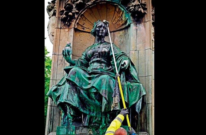 Workers clean a statue of Britain-s Queen Victoria that was defaced in Leeds
