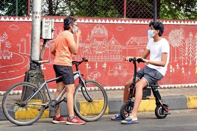With restrictions being gradually lifted to allow for more movement of people and vehicles, two cyclists, wearing protective masks, stop for a chat at Walkeshwar. PIC/BIPIN KOKATE