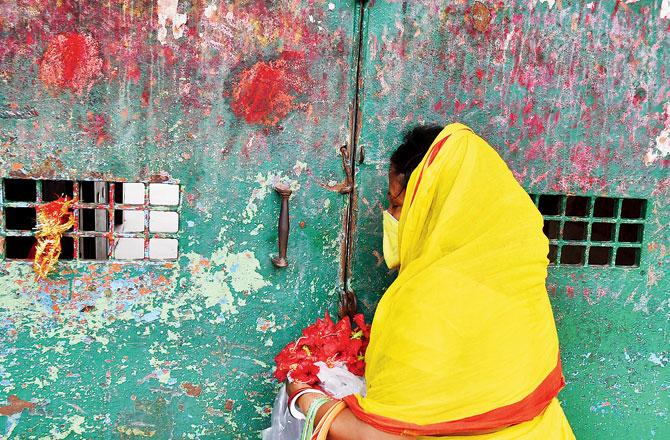A devotee offers prayer outside the closed gate of Kalighat Kali temple on the occasion of Bipodtarini puja in Kolkata on Saturday. Pics/PTI